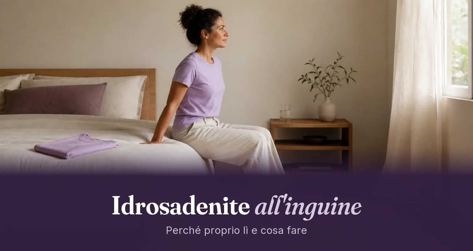 Donna seduta sul bordo del letto con pantaloni di lino larghi, che guarda verso la finestra nella luce del mattino